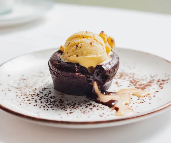 Volcán de chocolate con helado de vainilla en un plato blanco decorado.