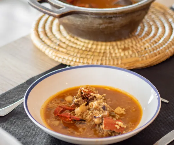 Plato de arroz caldoso con mariscos en una mesa con olla de fondo.
