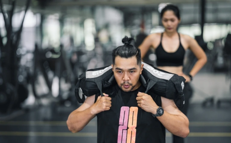 Sandbag lunges HYROX por parejas mixto