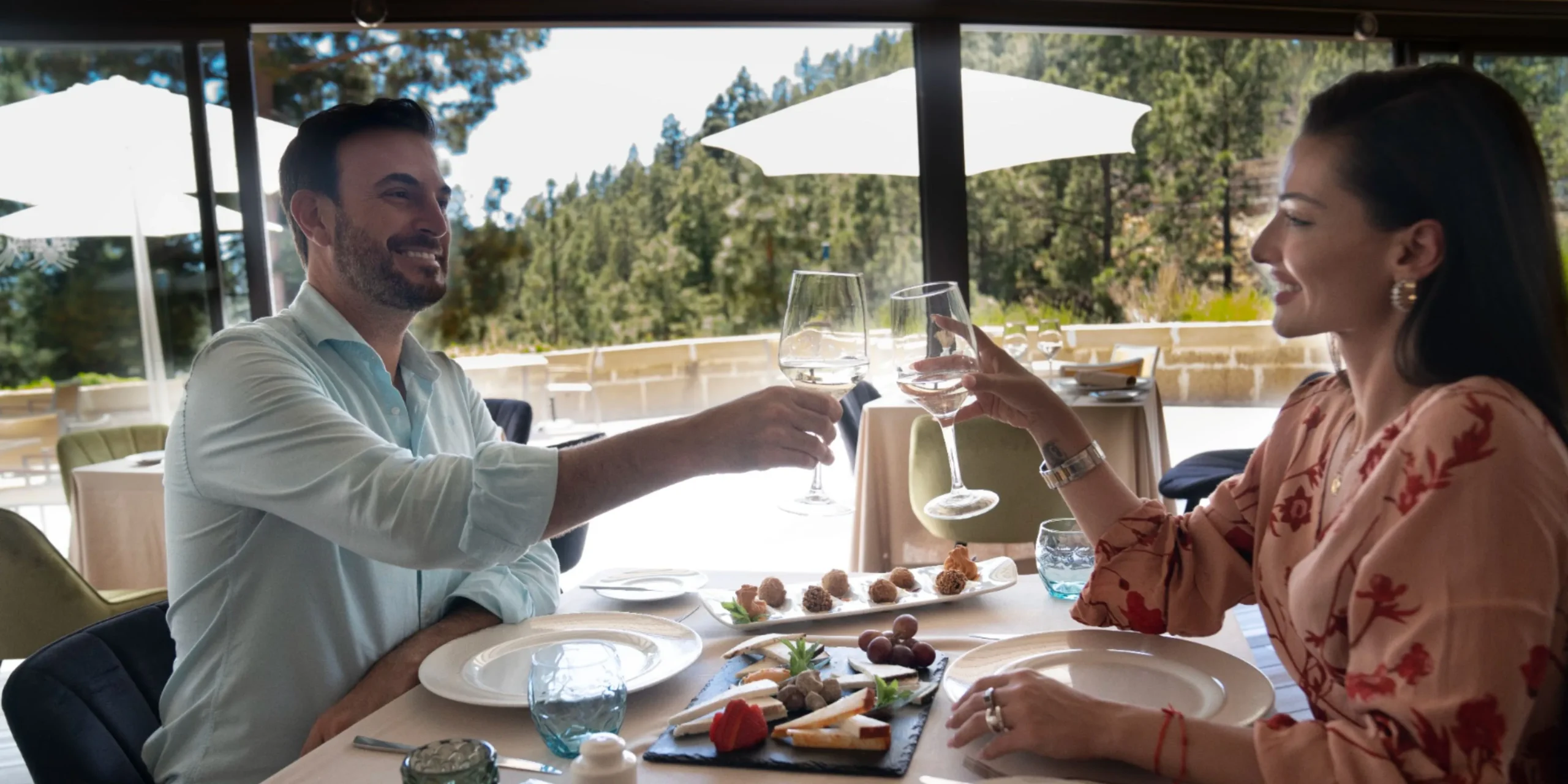 Pareja brindando con vino blanco durante una cena romántica al aire libre en Tenerife.