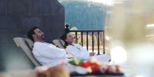 Couple relaxing on sun loungers on a hotel terrace in Tenerife with white bathrobes and views of nature, a relaxing midweek getaway.