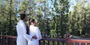 Couple with bathrobes on the terrace of Hotel Spa Villalba contemplating a pine forest.