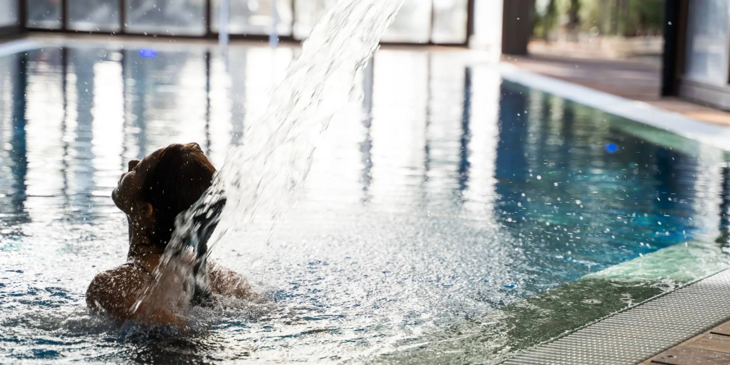 Persona recibiendo un chorro de agua de hidromasaje en la piscina climatizada del spa del Hotel Spa Villalba.