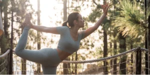 Mujer haciendo la postura del bailar&iacute;n de yoga al aire libre en el Spa Hotel Villalba.
