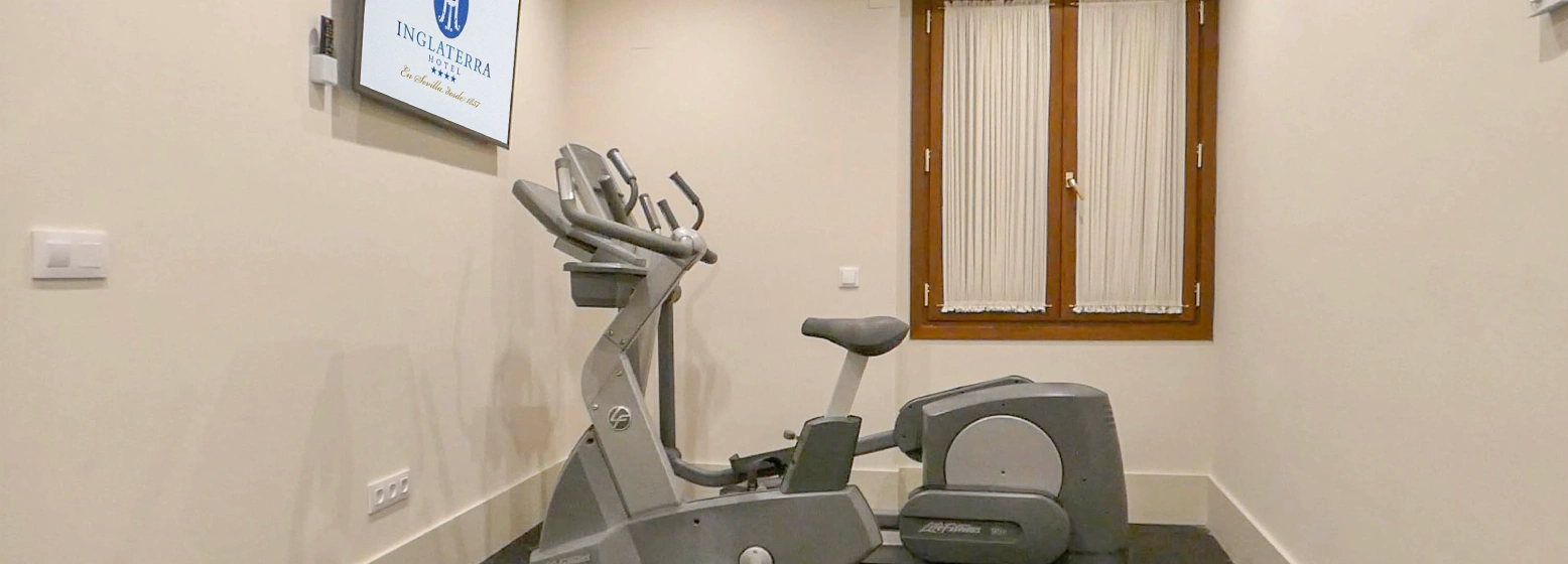 Gimnasio con bicicleta est&aacute;tica y m&aacute;quinas de ejercicios en una sala interior