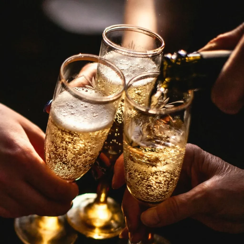 Copas de champ&aacute;n con burbujas en celebraci&oacute;n, manos brindando.