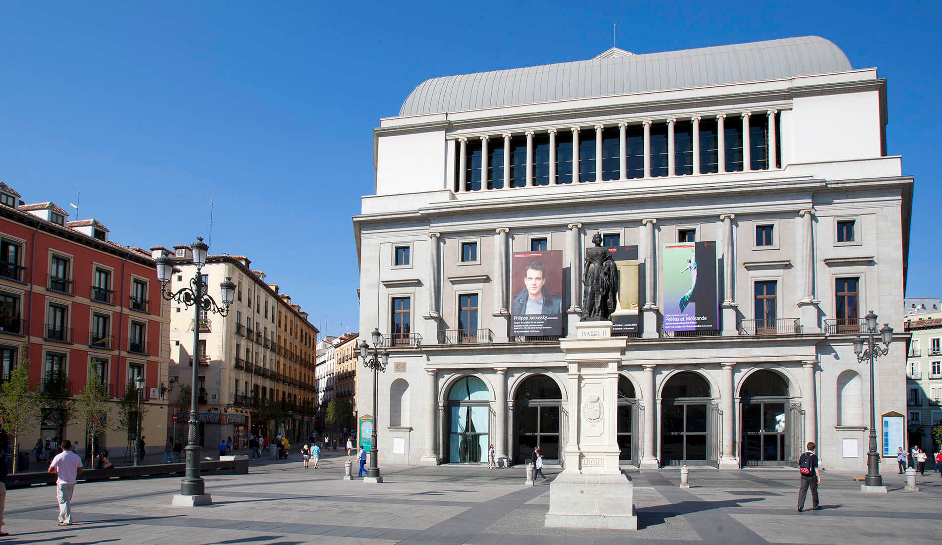 Una plaza amplia con edificios históricos y una estatua central bajo un cielo azul.