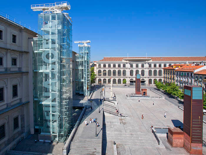 Plaza exterior del Museo Reina Sofía, con ascensores de cristal y columnas modernas.
