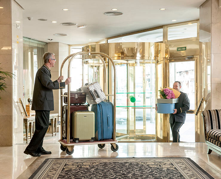 Un botones empuja un carrito con maletas en el vestíbulo de un hotel elegante.