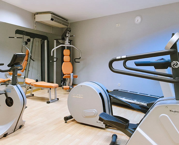 Gimnasio con máquinas de ejercicio, incluida una bicicleta, pesas y una cinta para correr.