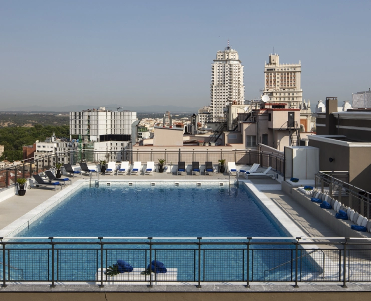 Piscina en azotea con vista a rascacielos en la ciudad durante un día soleado.